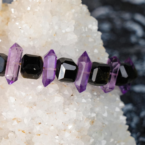 This Tara&#39;s Light bracelet features a stunning Amethyst double-terminated point, known for its ability to amplify spiritual energy and promote balance, along with grounding Golden Obsidian to shield against negative influences.